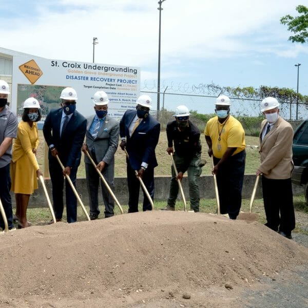 people in professional clothing and hard hats holding shovels on a pile of dirt