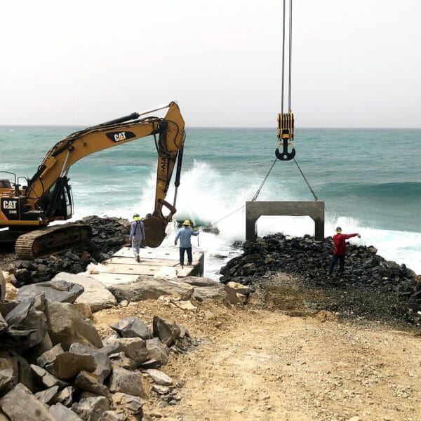 crane and construction workers working near the ocean